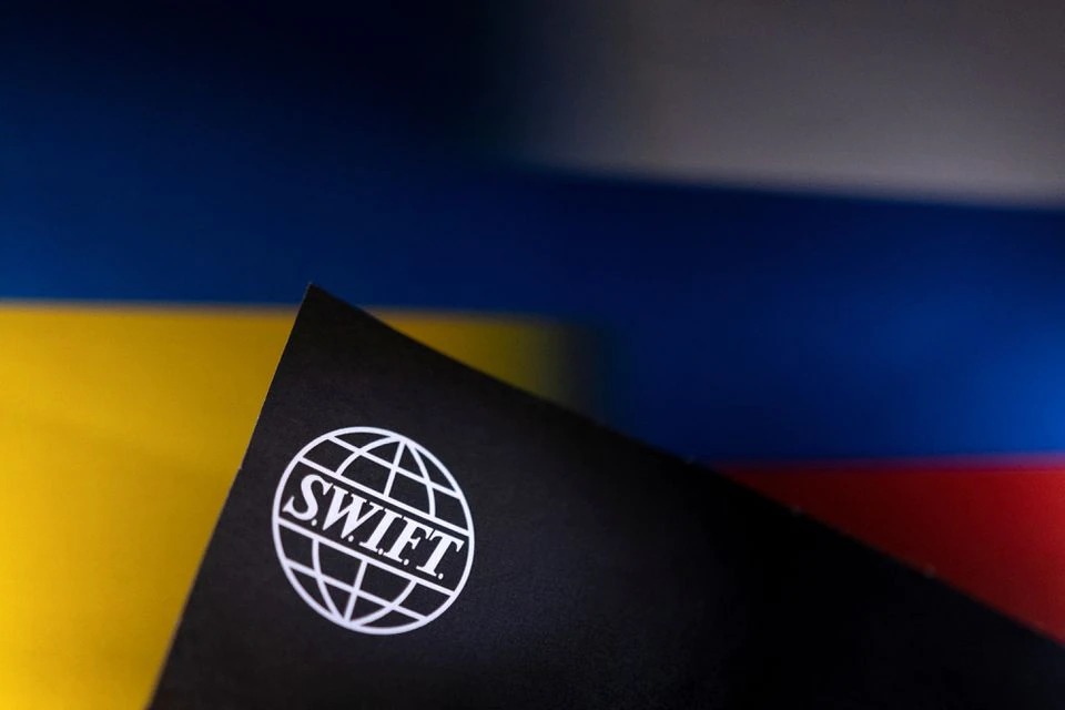Logo SWIFT đặt trên nền cờ Nga và Ukraine. Ảnh: Reuters