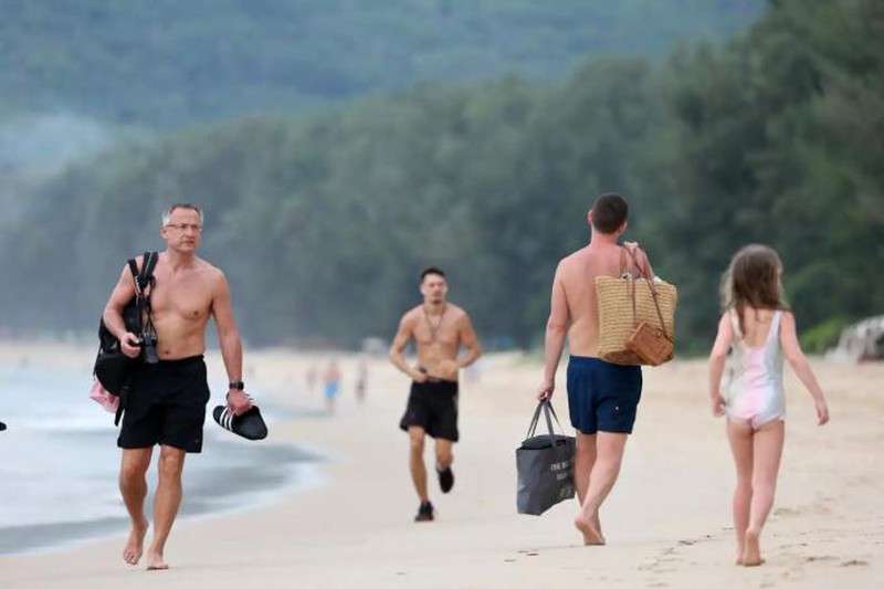 Du khách đi dạo trên một bãi biển ở Phuket, Thái Lan. Ảnh: Reuters